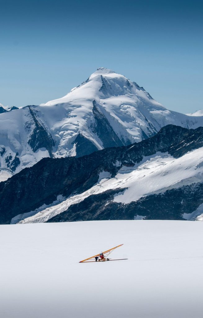 Small plane dwarfed by snowy mountain surroundings