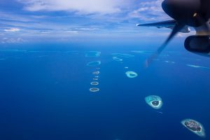 A view out of a twin propeller engine plane's window of the Maldives